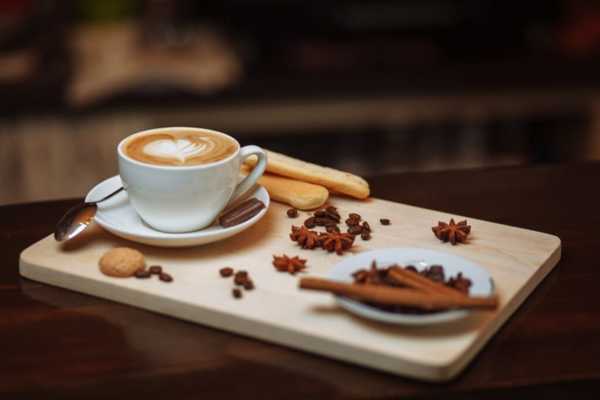 a cup of coffee with a heart on top of a plate with spices